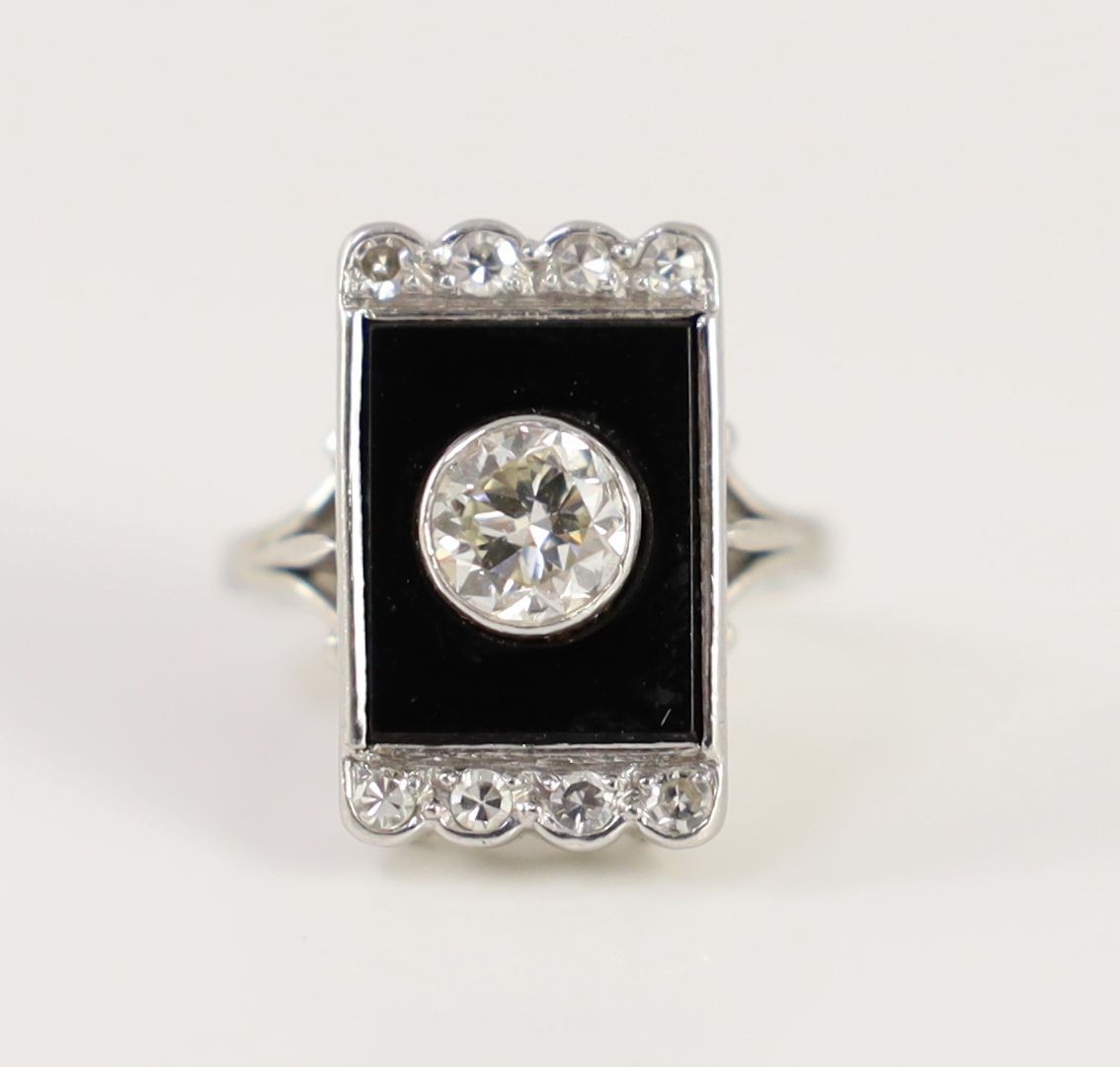 A platinum, single stone diamond and black onyx set rectangular tablet ring, with eight stone diamond setting